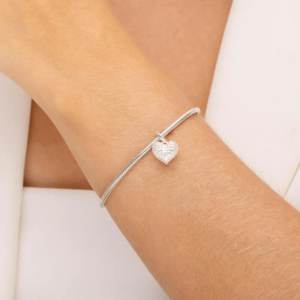 Mulher usando pulseira com berloque de coração em prata 925