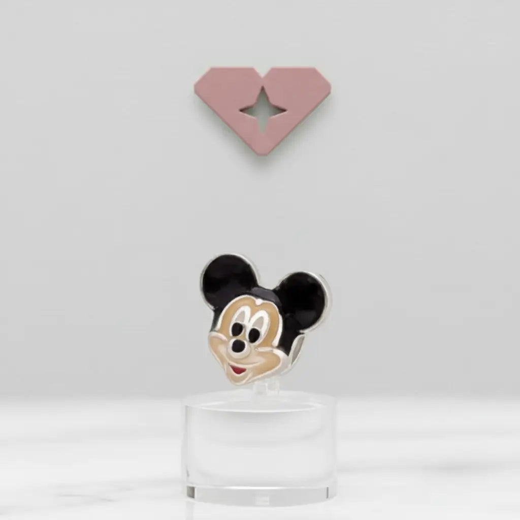 Berloque em Prata 925 formato Mickey, com detalhes esmaltados, exposto em pedestal transparente.