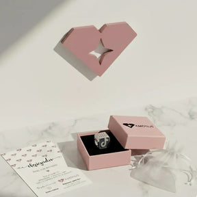 Berloque TikTok de prata 925 com logotipo cravejado, apresentado em caixa rosa da marca Amorus sobre fundo claro.