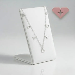 Colar choker prata 925 com pingentes de corações lisos e vazados, exposto em suporte branco — joia romântica e elegante.
