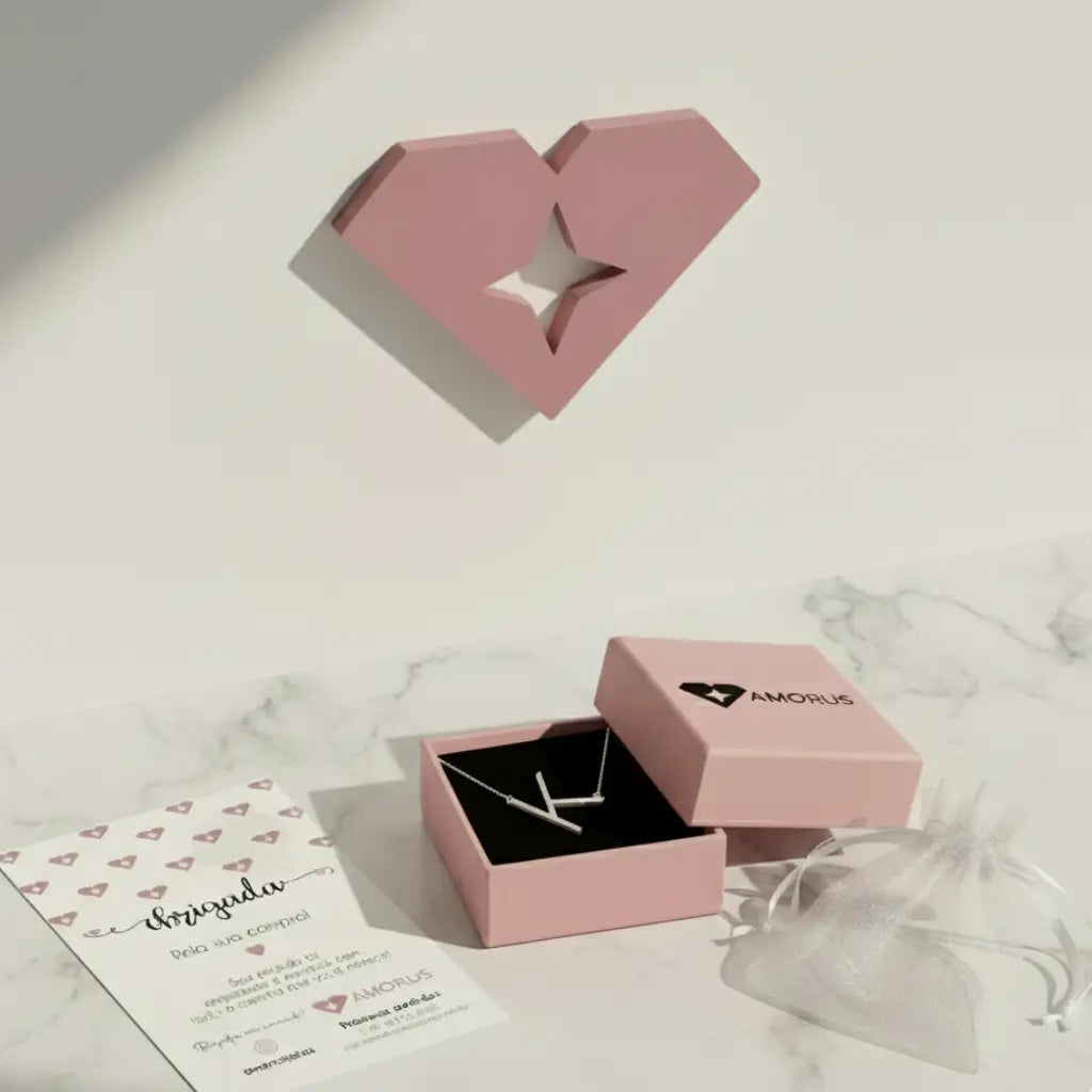 Colar com letra K em prata 925 dentro de caixa rosa da AMORUS com saquinho de presente ao lado.