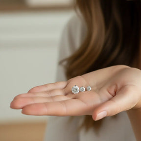 Trio de brincos ponto de luz prata 925 com zircônias, mostrado na mão para comparação de tamanhos.